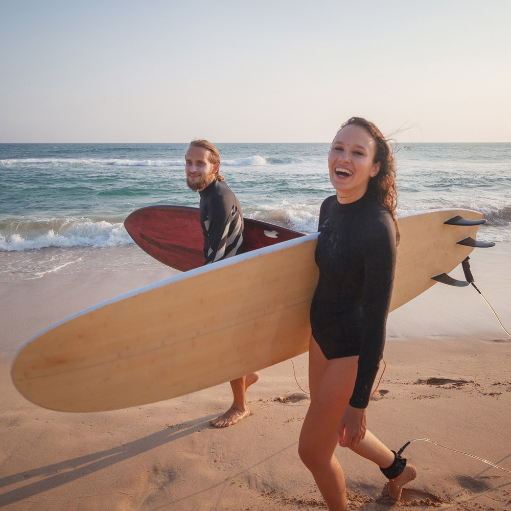 Young couple of happy smiling surfers on ocean coast, sport active lifestyle vacation travel concept.