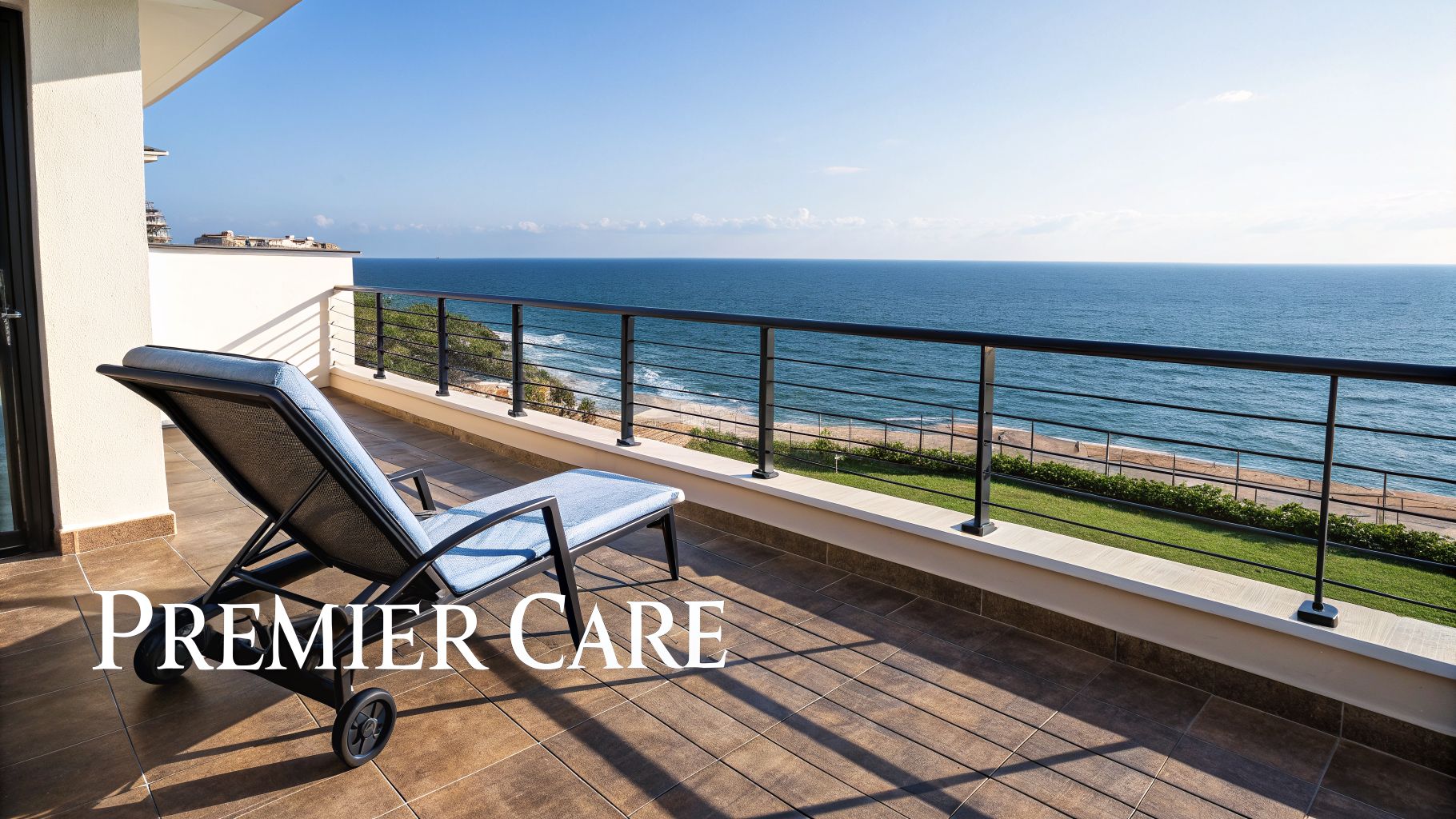 An oceanfront balcony with a lounge chair overlooking the deep blue sea and sandy beach.