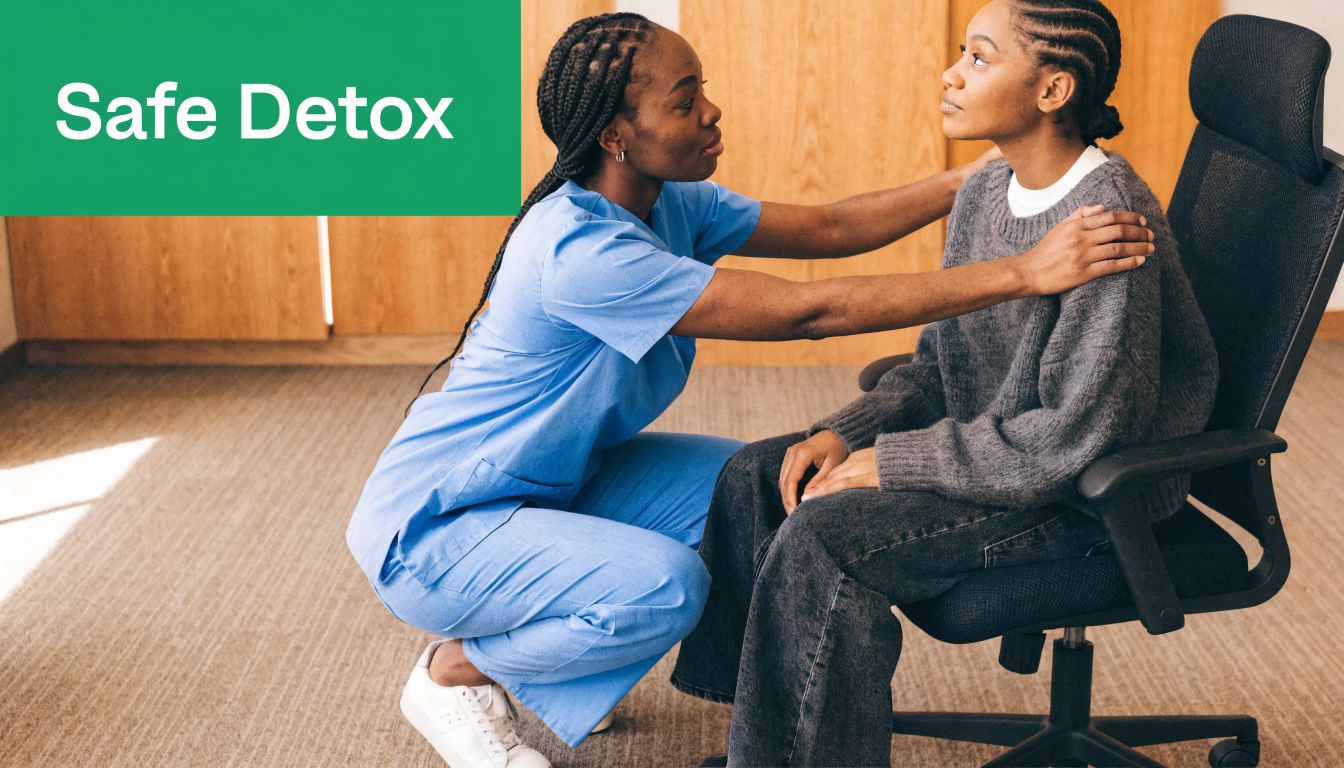 A caring nurse in blue scrubs comforts a young woman sitting in an office chair.